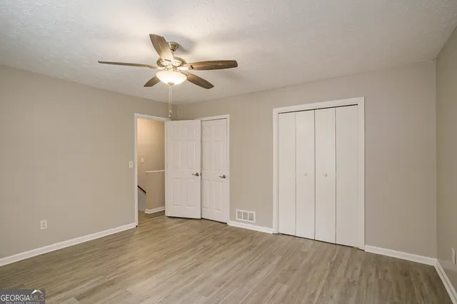 an empty room with wooden floor fan and windows