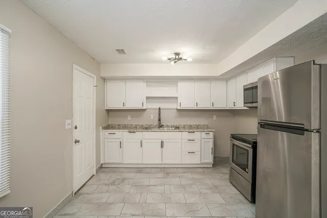 a kitchen with granite countertop cabinets stainless steel appliances and a counter space