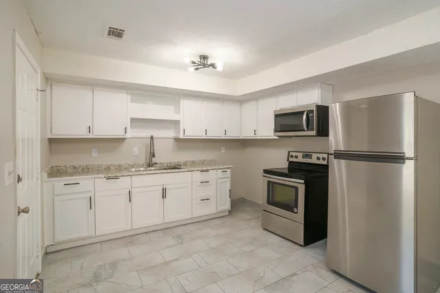 a view of a kitchen with a refrigerator and a sink