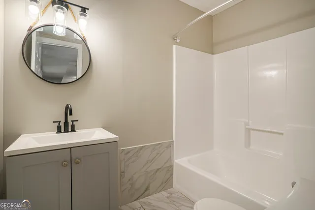 an empty room with wooden floor chandelier fan and windows