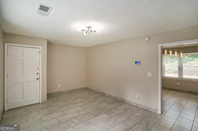 an empty room with chandelier fan and windows