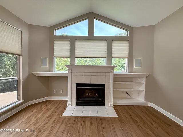 a view of an empty room with window and wooden floor