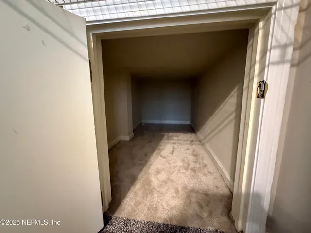 a view of an empty room with chandelier fan and a window