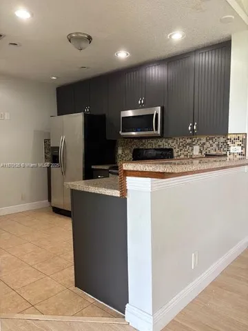 a kitchen with stainless steel appliances granite countertop a refrigerator and a microwave