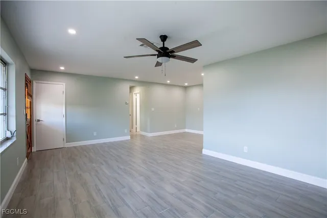 a view of an empty room with wooden floor and a window