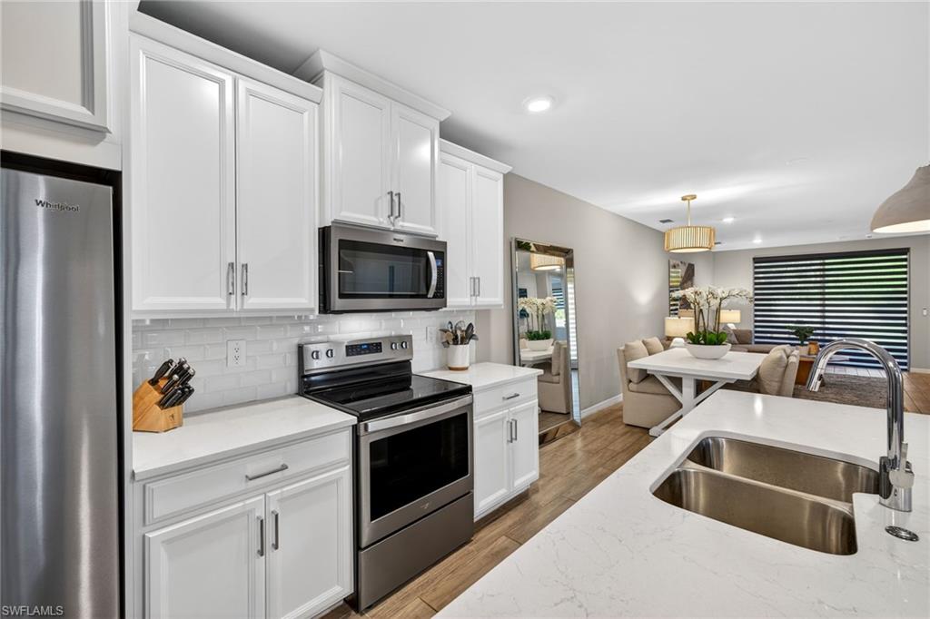14567 Edgewater Circle Naples, FL 34114 - Photo 9 of 43 a kitchen that has a sink and a stove top oven