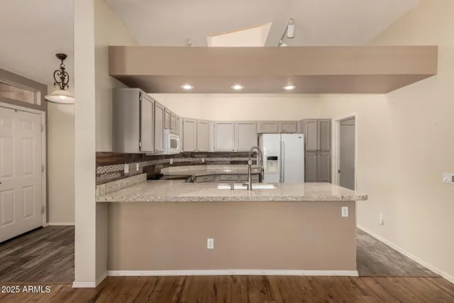 a large white kitchen with a sink a large window and stainless steel appliances