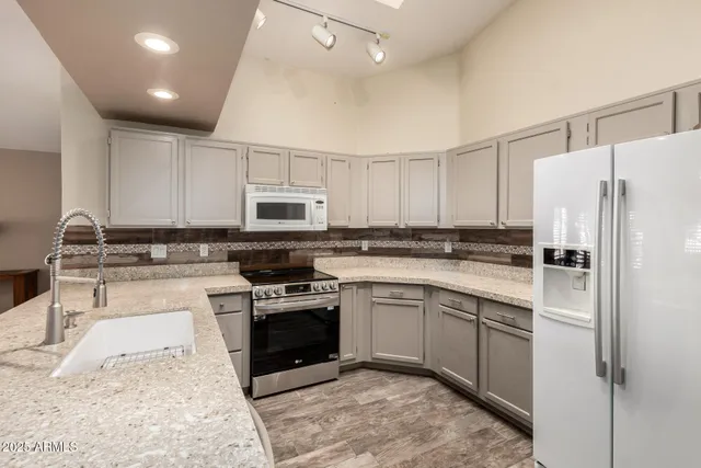 a kitchen with stainless steel appliances granite countertop a stove a sink and a refrigerator