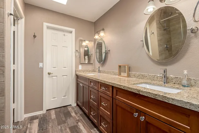 a bathroom with a granite countertop double vanity sink and a mirror