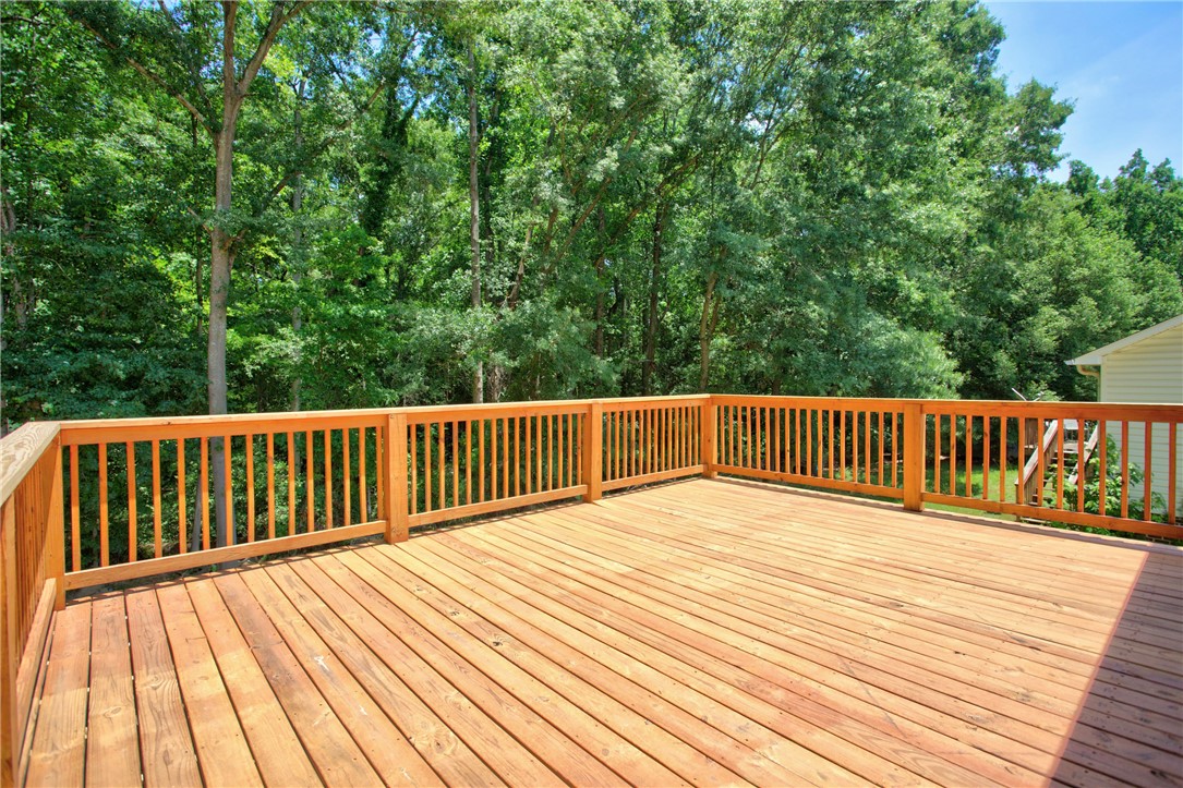 223 Maple Drive Anderson, SC 29621 - Photo 31 of 45 A spacious wooden deck provides a tranquil outdoor retreat amidst lush greenery.