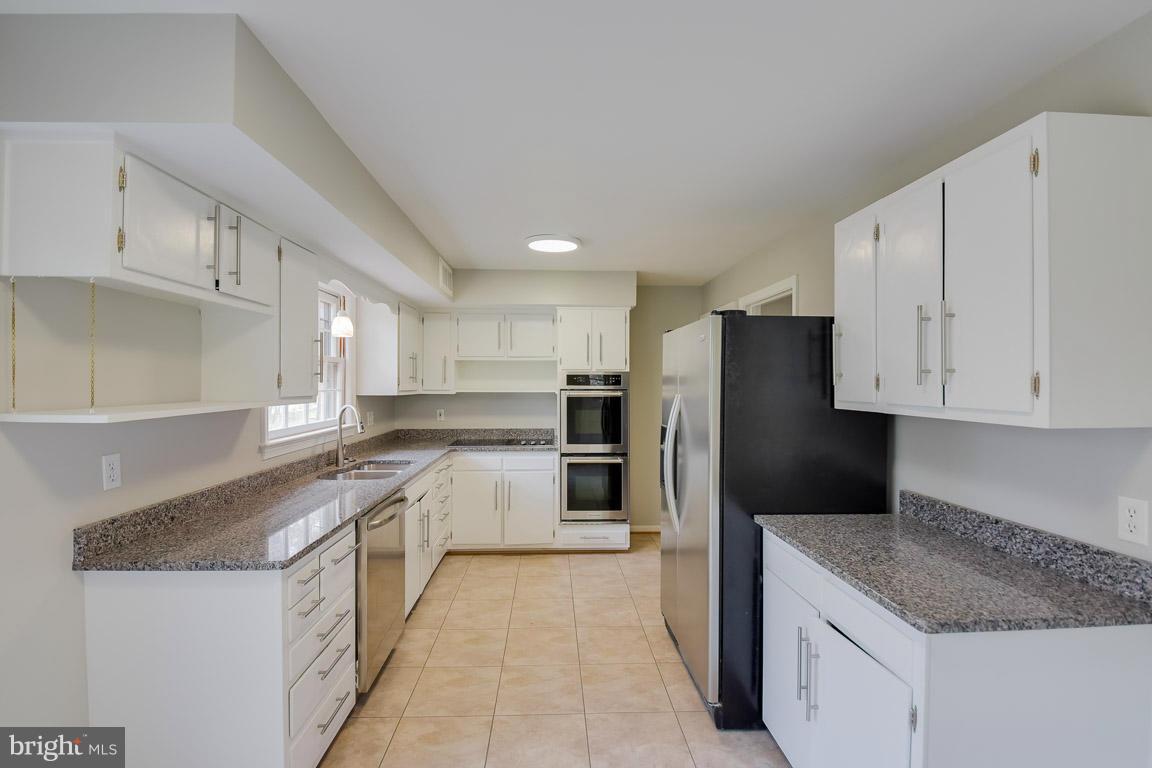 6716 Huntsman Boulevard Springfield, VA 22152 - Photo 5 of 30 a kitchen with stainless steel appliances granite countertop a refrigerator sink and cabinets