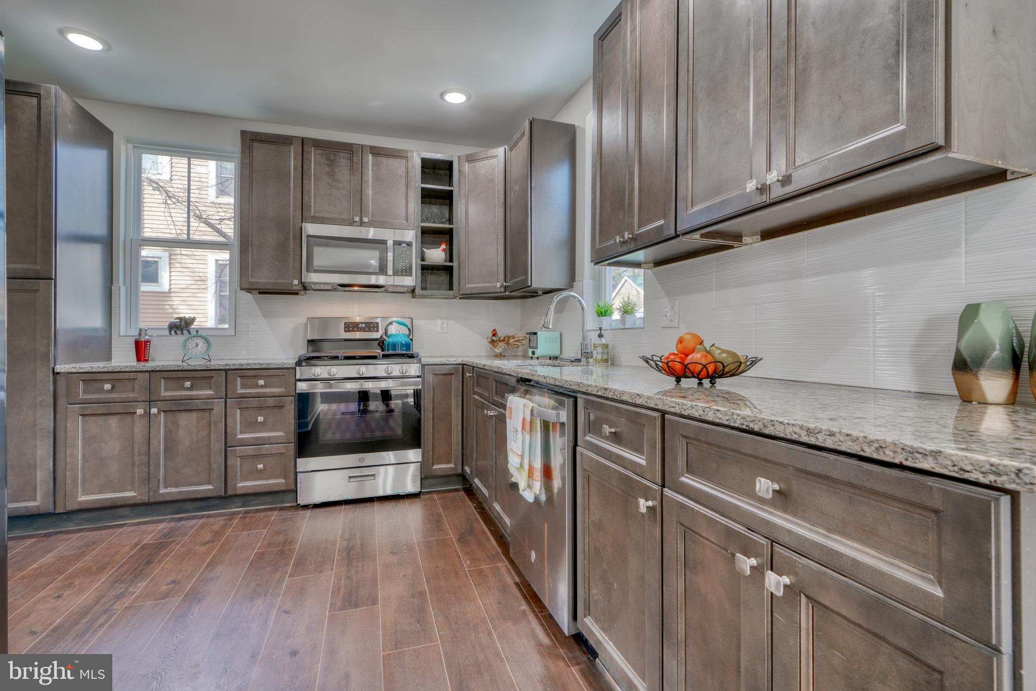 231 Mallow Hill Road Baltimore, MD 21229 - Photo 18 of 48 a kitchen with stainless steel appliances granite countertop wooden cabinets granite counter tops and a hard wood floors