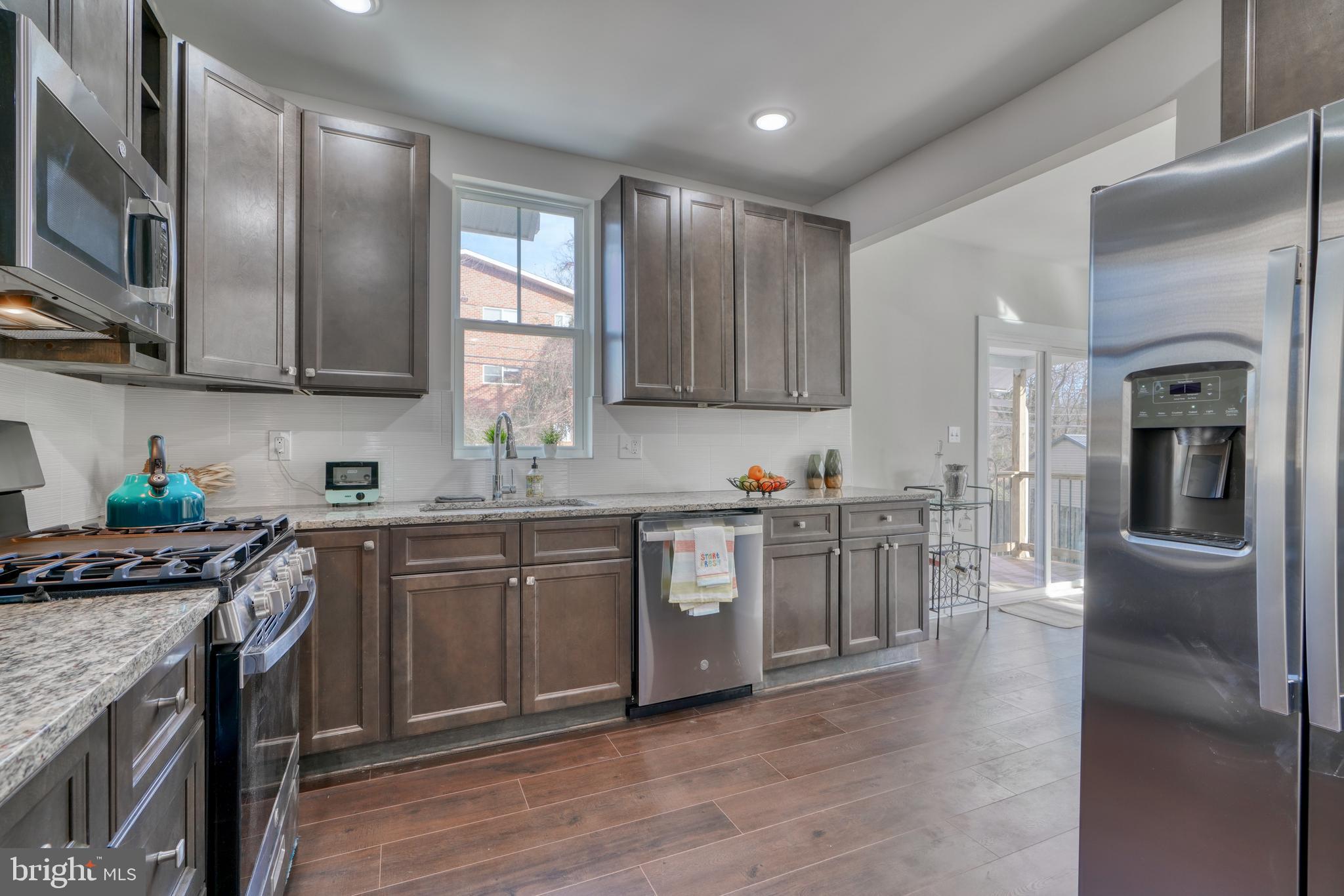 231 Mallow Hill Road Baltimore, MD 21229 - Photo 20 of 48 a kitchen with stainless steel appliances granite countertop a refrigerator a sink dishwasher a stove with wooden cabinets and floor