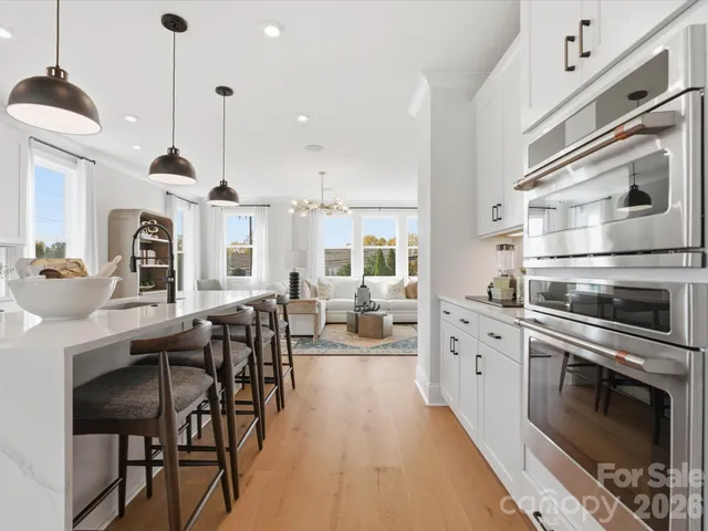 a kitchen with stainless steel appliances kitchen island granite countertop a stove a sink a dining table and chairs with wooden floor