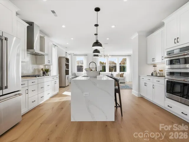 a kitchen with stainless steel appliances kitchen island granite countertop a stove a sink and a refrigerator