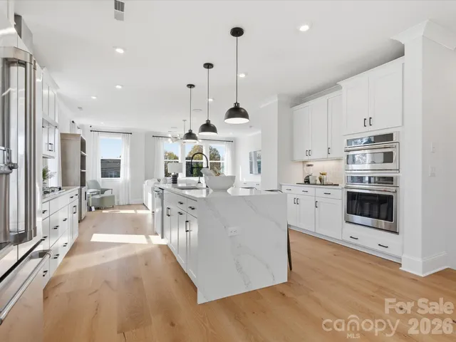 a large white kitchen with cabinets a sink and stainless steel appliances