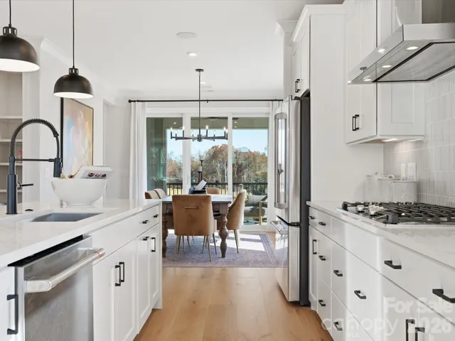 a kitchen with kitchen island a counter space a sink a stove and white cabinets with wooden floor