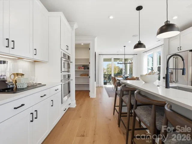 a kitchen with stainless steel appliances a dining table chairs and white cabinets
