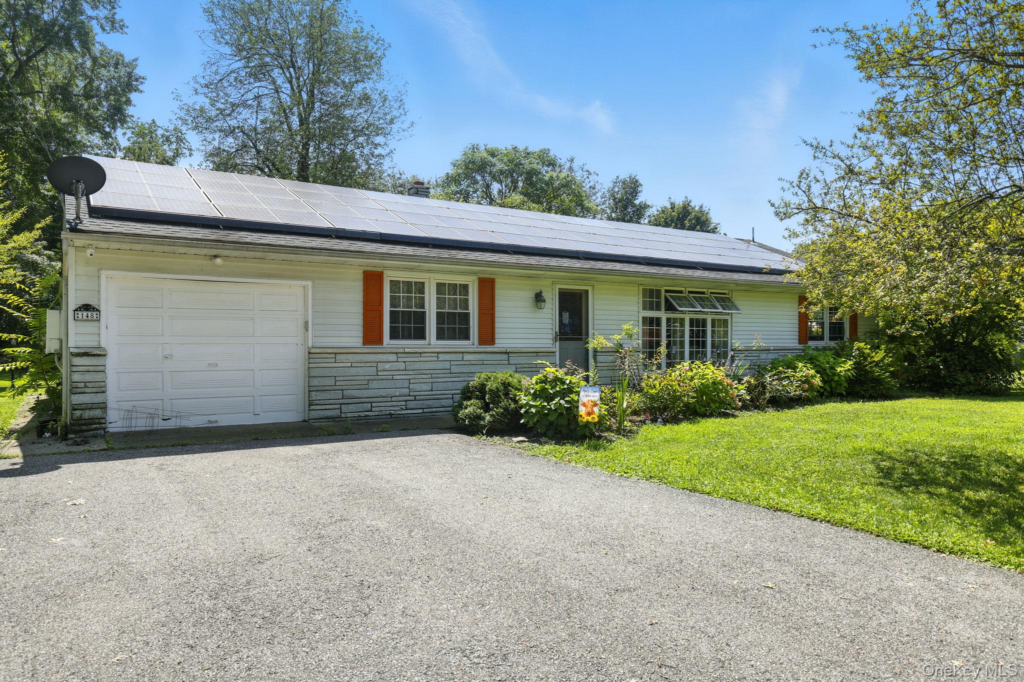 a view of a house with a yard plants and large tree