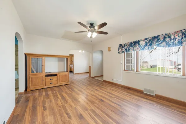 a view of a big room with wooden floor a ceiling fan and windows