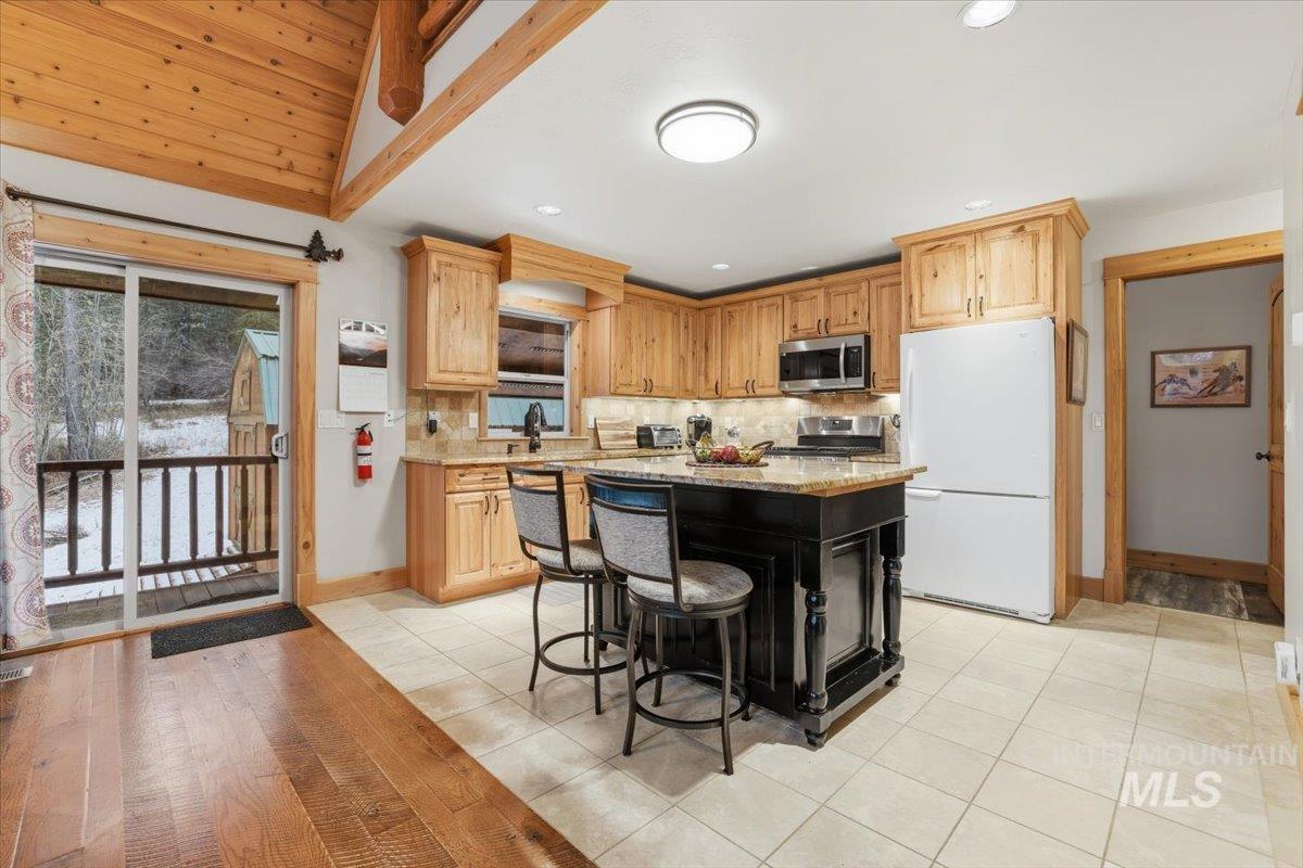 20 Valley High Road Garden Valley, ID 83622 - Photo 13 of 46 Kitchen with light tile patterned floors, stainless steel appliances, light stone counters, a center island, and a breakfast bar