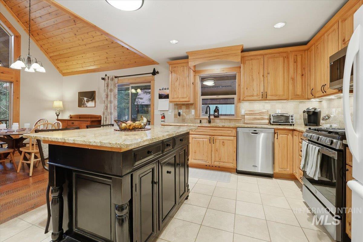 20 Valley High Road Garden Valley, ID 83622 - Photo 14 of 46 Kitchen with hanging light fixtures, light stone countertops, appliances with stainless steel finishes, tasteful backsplash, and wood ceiling