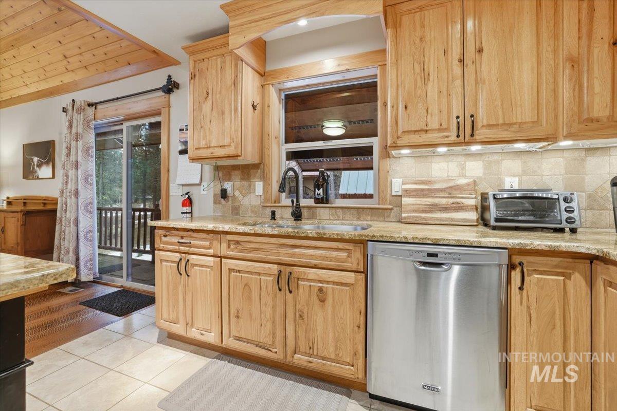 20 Valley High Road Garden Valley, ID 83622 - Photo 15 of 46 Kitchen featuring dishwasher, tasteful backsplash, light tile patterned flooring, light stone countertops, and wooden ceiling