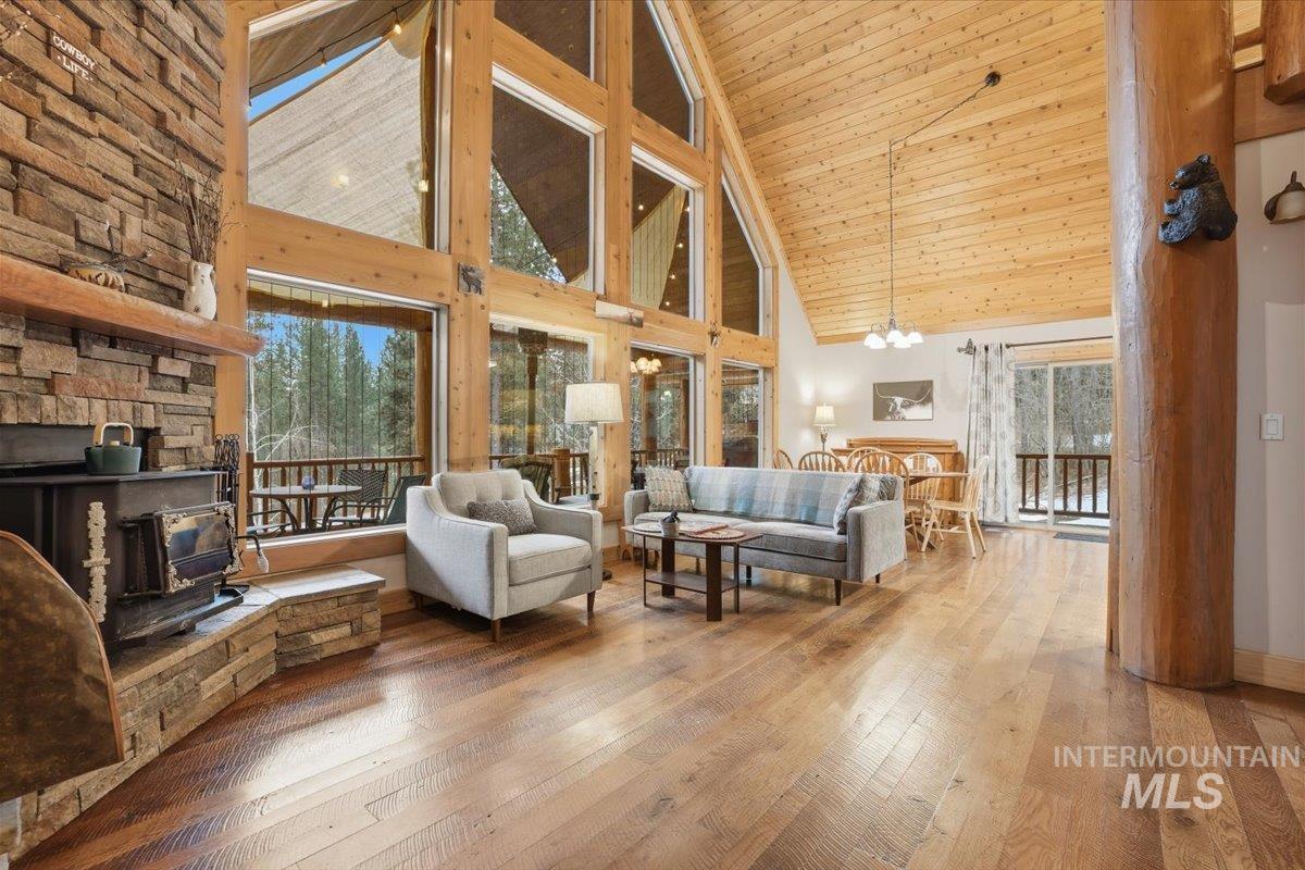 20 Valley High Road Garden Valley, ID 83622 - Photo 7 of 46 Living area with high vaulted ceiling, a wood stove, wood-type flooring, wooden ceiling, and a chandelier