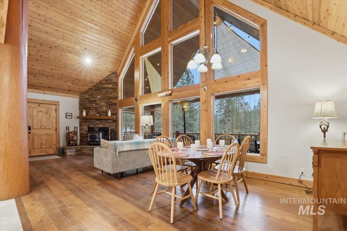 20 Valley High Road Garden Valley, ID 83622 - Photo 9 of 46 Dining space featuring wood ceiling, high vaulted ceiling, a stone fireplace, hardwood / wood-style flooring, and a chandelier