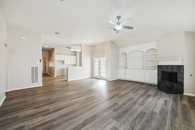 a view of an empty room with wooden floor and a fireplace