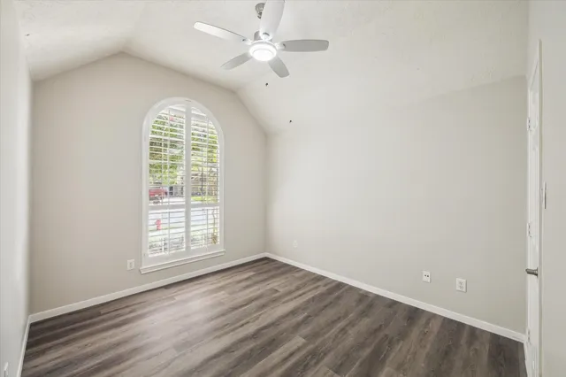 an empty room with wooden floor chandelier fan and windows