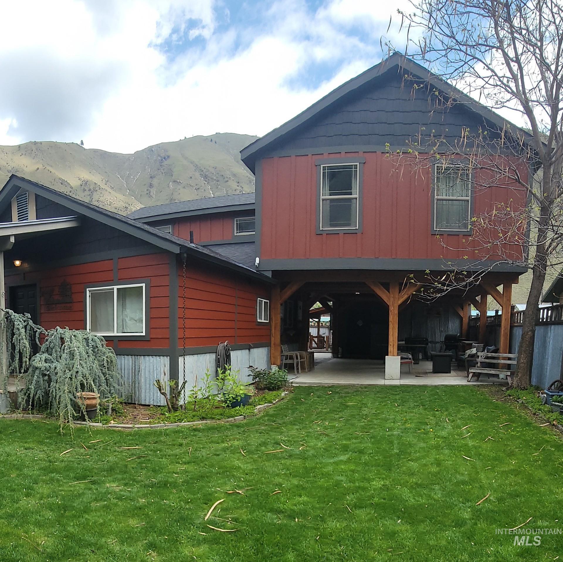 Front view of property featuring a lawn, a patio, and a mountain view