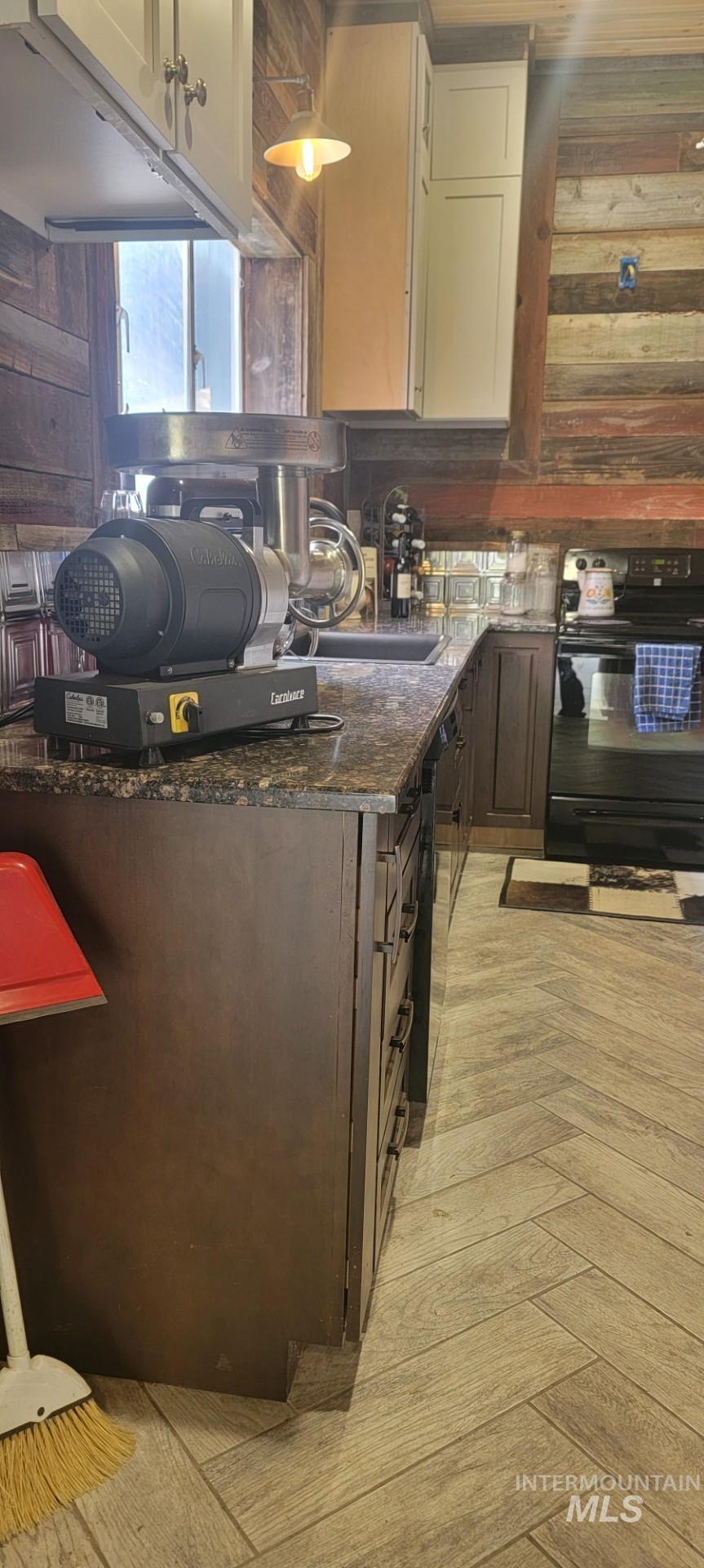 1006 Borah Avenue Riggins, ID 83549 - Photo 16 of 23 Kitchen featuring black appliances, dark stone countertops, parquet floors, wooden walls, and dark wood finish cabinetry
