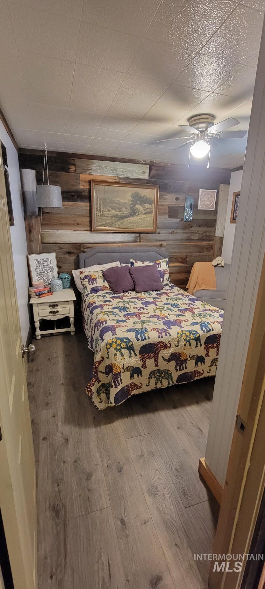 1006 Borah Avenue Riggins, ID 83549 - Photo 18 of 23 Bedroom featuring hardwood / wood-style flooring, wood walls, and a ceiling fan