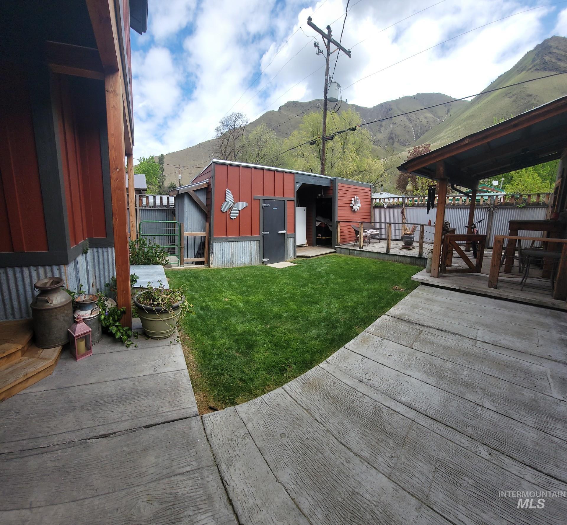 1006 Borah Avenue Riggins, ID 83549 - Photo 5 of 23 Fenced backyard with an outdoor structure, a mountain view, and outdoor dining area