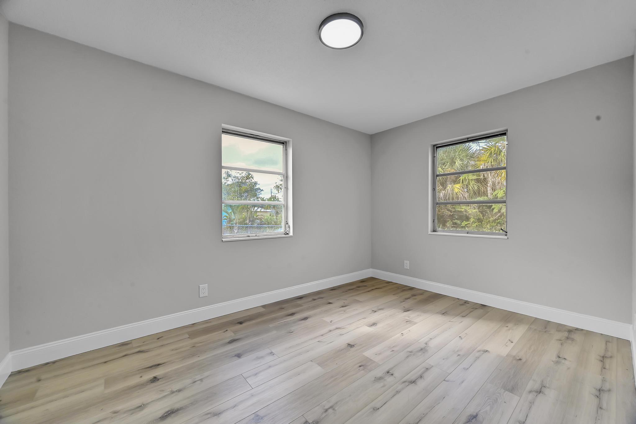 8487 Southeast Begonia Way Hobe Sound, FL 33455 - Photo 17 of 26 an empty room with wooden floor and windows