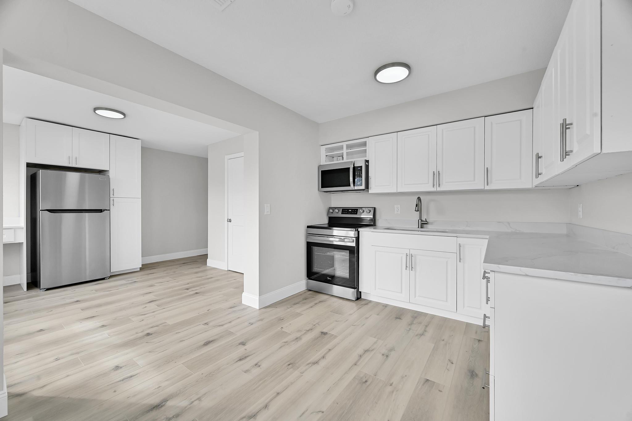 8487 Southeast Begonia Way Hobe Sound, FL 33455 - Photo 7 of 26 a kitchen with a refrigerator stove and white cabinets
