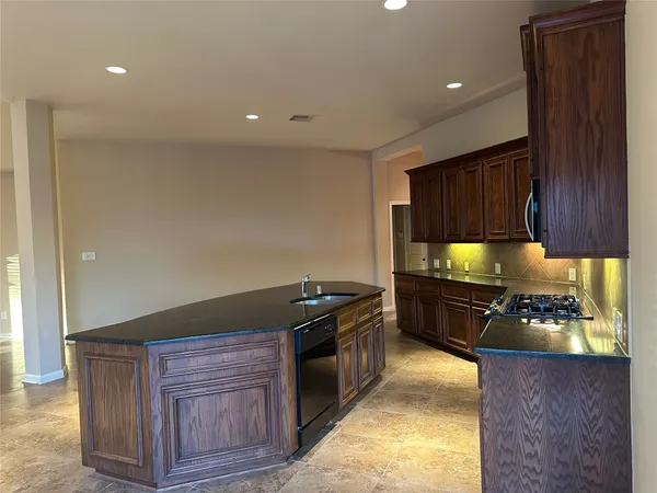 a kitchen with kitchen island granite countertop a sink a stove and a refrigerator
