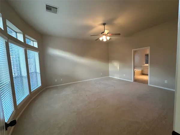 en empty room with windows and chandelier fan