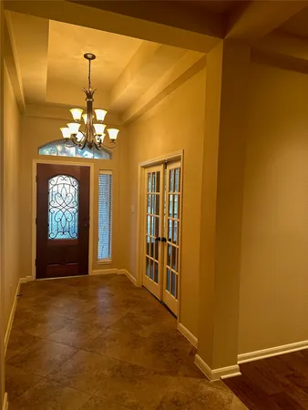 a view of a hallway with windows and chandelier