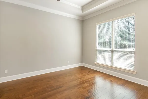 an empty room with wooden floor chandelier fan and windows