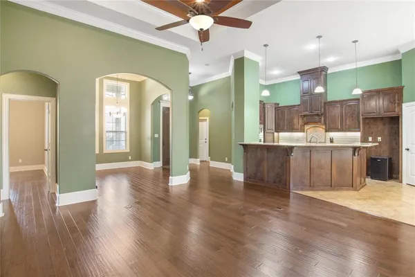 a room with stainless steel appliances kitchen island granite countertop a refrigerator a sink a dining table and chairs with wooden floor