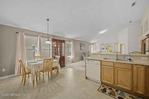 a dining hall with stainless steel appliances granite countertop a sink and chairs