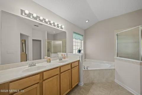 a spacious bathroom with a double vanity sink a mirror and a bathtub