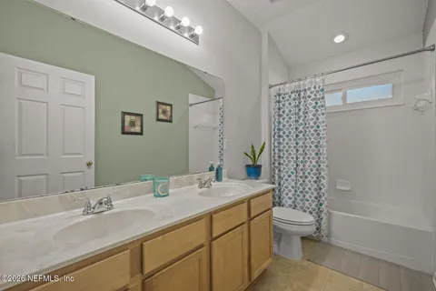 a bathroom with double vanity sink a toilet a shower and a mirror