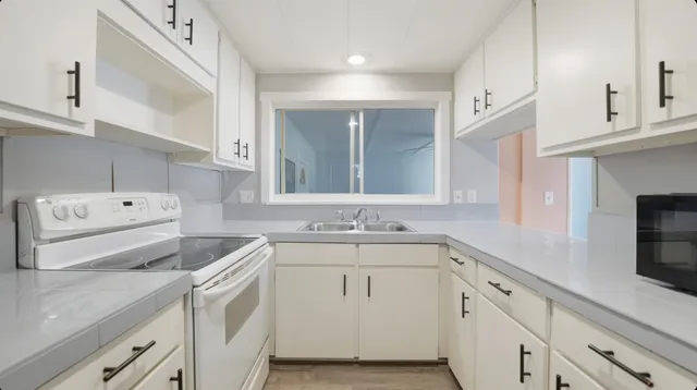 a kitchen with a sink dishwasher and white cabinets with wooden floor
