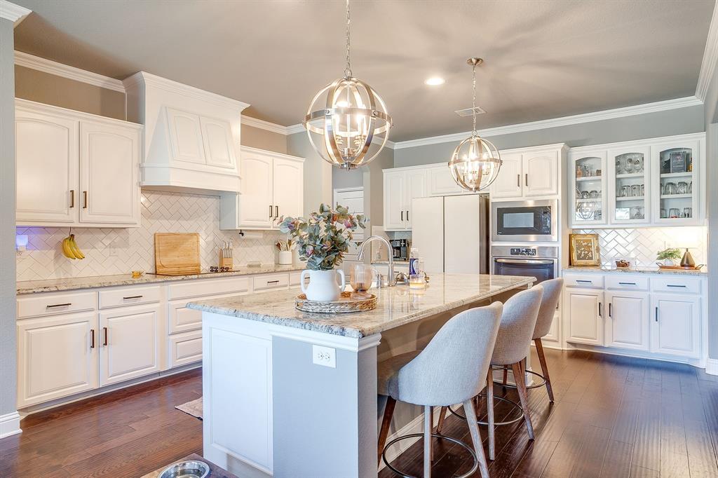 112 Lone Star Way Godley, TX 76044 - Photo 12 of 40 a kitchen with stainless steel appliances a table chairs and chandelier