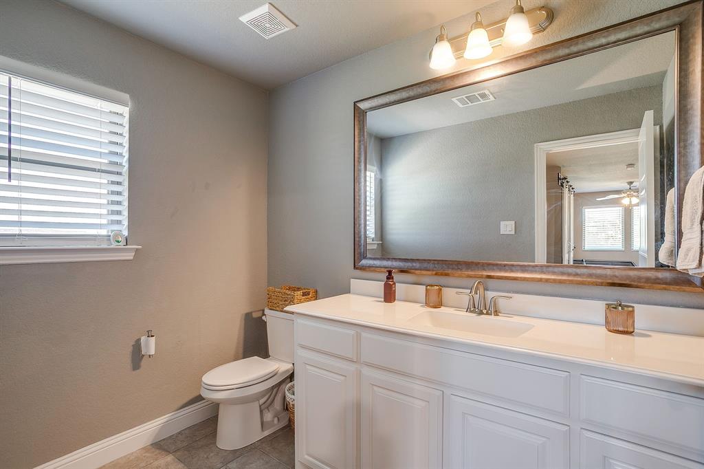 112 Lone Star Way Godley, TX 76044 - Photo 16 of 40 a bathroom with a toilet a sink and mirror