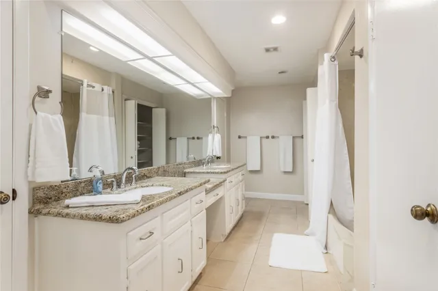 a bathroom with a granite countertop sink a mirror a bathtub and shower