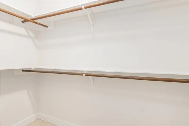 a view of an empty room with chandelier fan and wooden floor